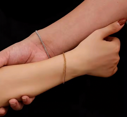 Two wrists with gold and silver bracelets on a black background